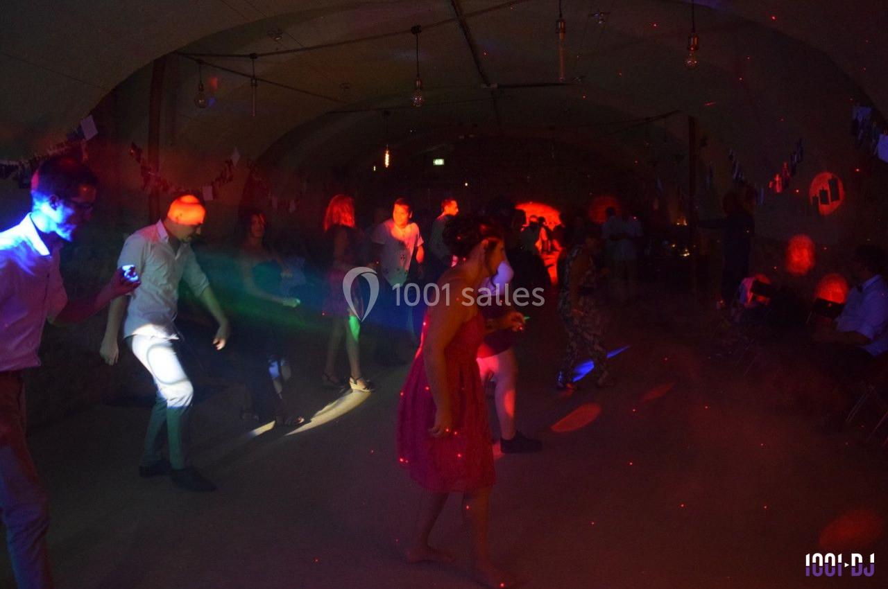 Personnes dansant sous des lumières colorées dans une salle sombre décorée pour une fête.