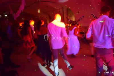 Des personnes dansent sous des lumières colorées dans une ambiance festive et tamisée.