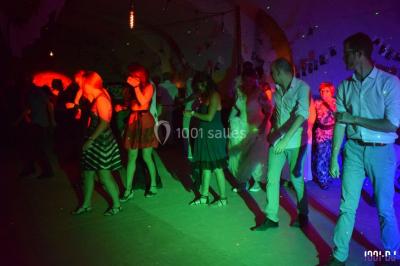 Des personnes dansent sous des lumières colorées dans une ambiance festive et tamisée.