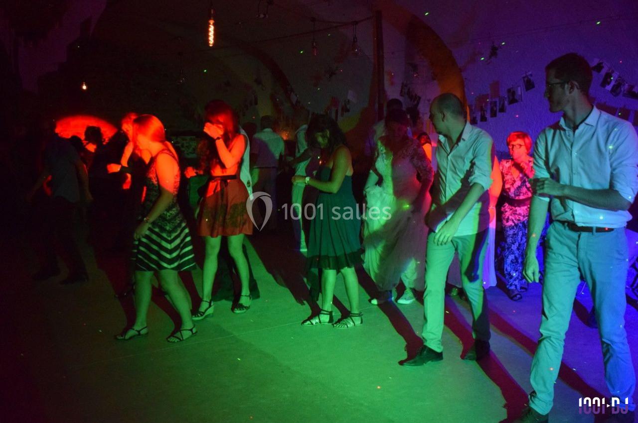 Personnes dansant en ligne dans une salle faiblement éclairée avec des lumières colorées.