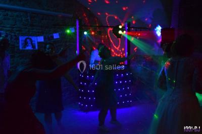 Des personnes dansent sous des lumières colorées dans une ambiance festive et tamisée.