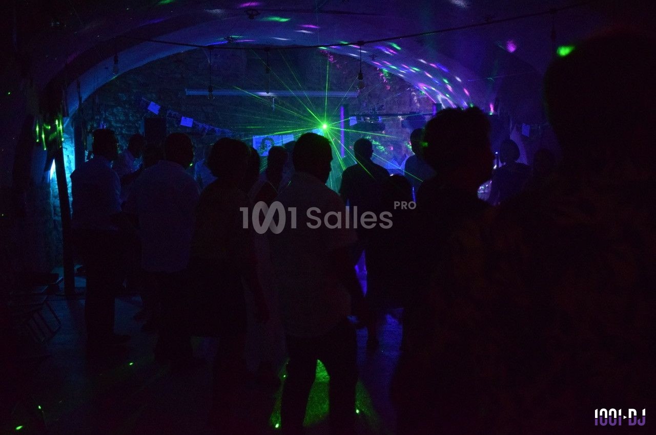 Personnes dansant dans une salle sombre éclairée par des lumières colorées et des effets laser.