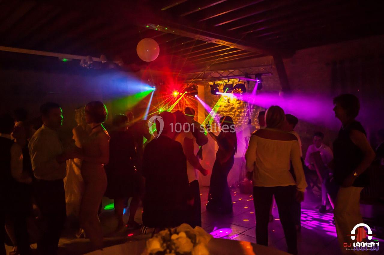 Groupe de personnes dansant sous des lumières colorées dans une salle avec un plafond en bois.