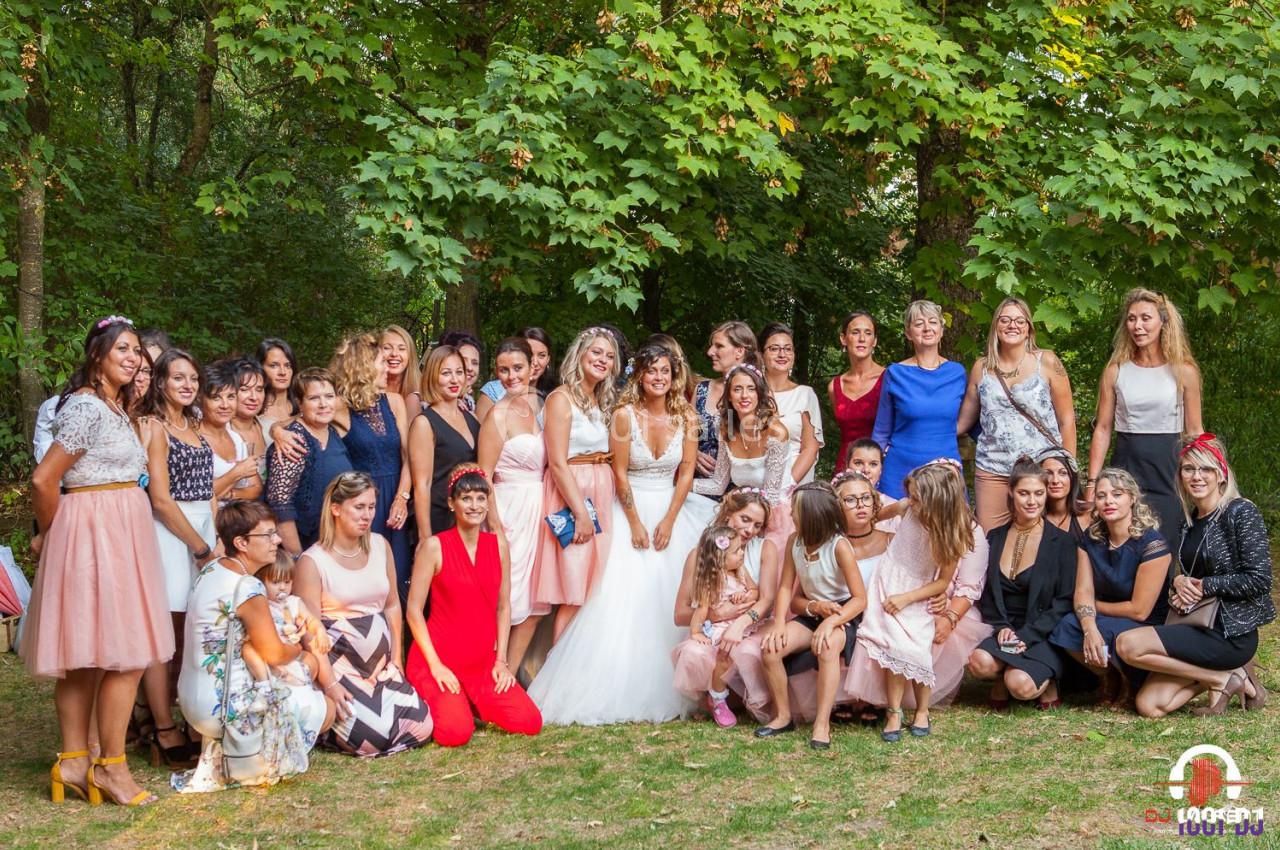 Groupe de femmes posant en extérieur dans un parc, certaines en tenue de cérémonie, entourées de verdure.