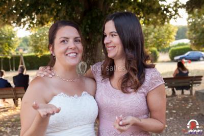 Des personnes dansent en ligne dans une salle décorée de ballons, avec des tables dressées et des convives en arrière-plan.