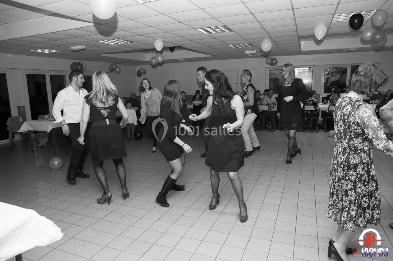 Des personnes dansent dans une salle décorée de ballons, lors d'un événement festif en intérieur.