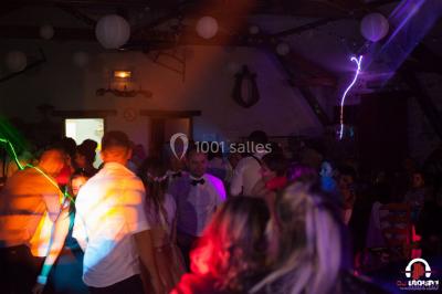 Des personnes dansent en ligne dans une salle décorée de ballons, avec des tables dressées et des convives en arrière-plan.