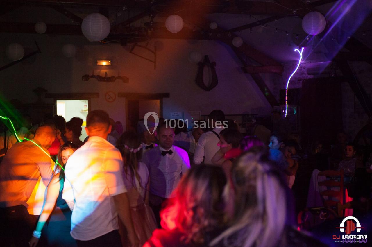 Groupe de personnes dans une salle sombre avec éclairages colorés, ambiance festive et décorations suspendues.