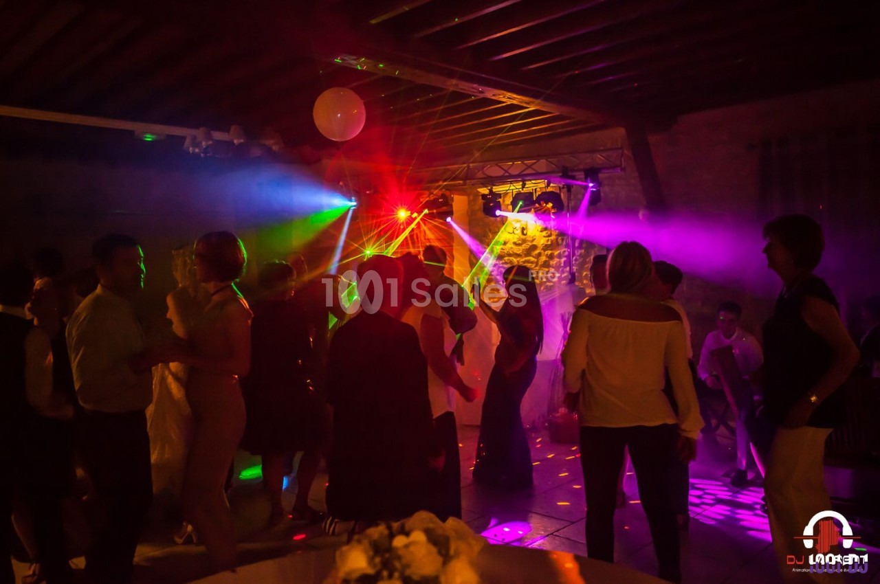 Groupe de personnes dansant sous des lumières colorées dans une salle avec un plafond en bois.