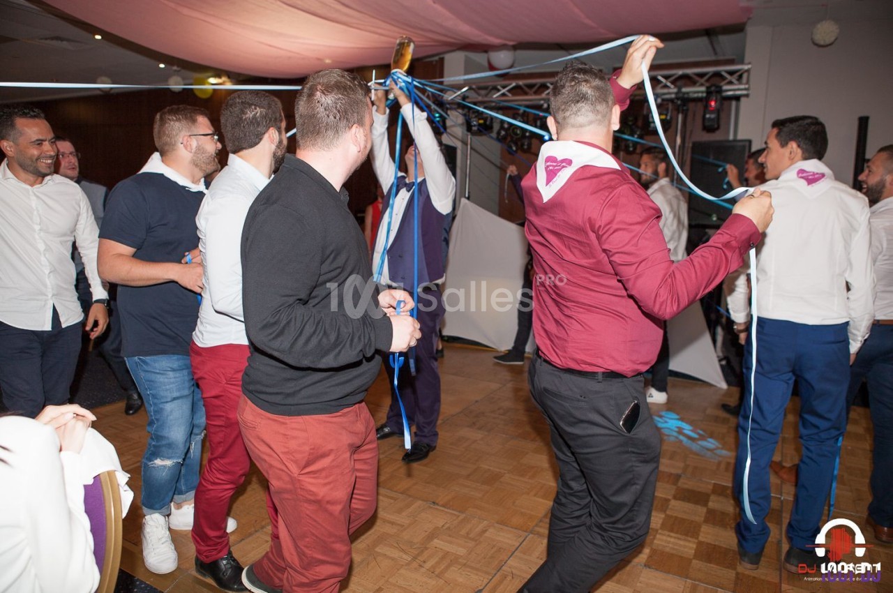 Des personnes dansent et s'amusent sur une piste lors d'une fête, tenant des rubans colorés.