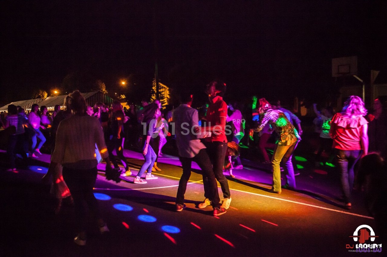 Des personnes dansent de nuit sur une piste éclairée par des lumières colorées.