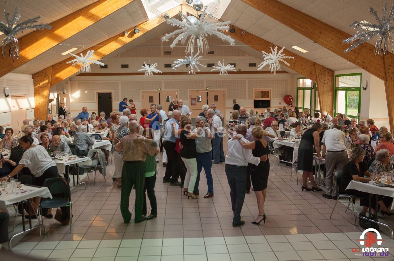Des personnes dansent et dînent dans une grande salle lumineuse avec une décoration festive au plafond.