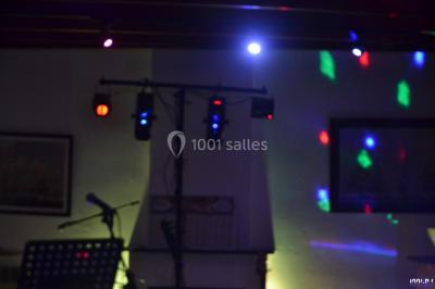 Des personnes dansent dans une ambiance festive avec des lumières colorées dans une salle sombre.