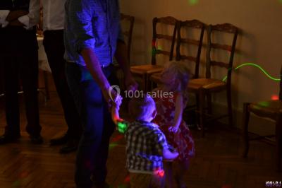 Des personnes dansent dans une ambiance festive avec des lumières colorées dans une salle sombre.