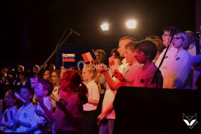 Des personnes dansent dans une ambiance festive avec des lumières colorées dans une salle sombre.