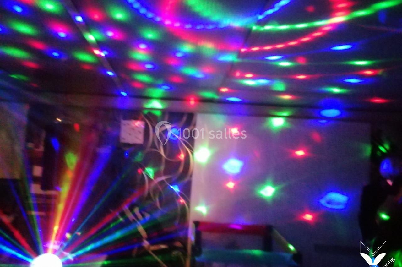 Effets lumineux colorés projetés sur un mur et un plafond dans une pièce sombre.