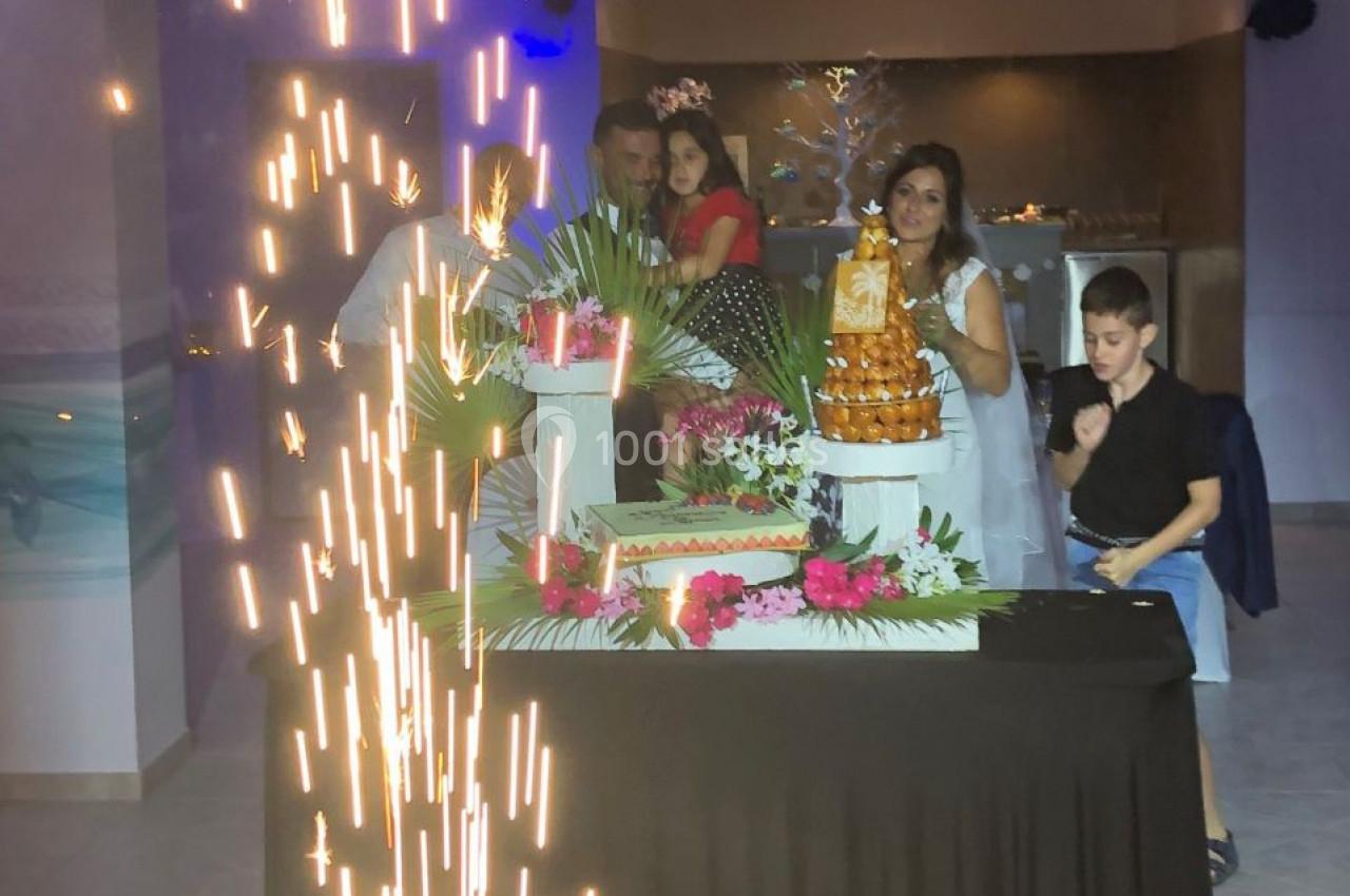 Des invités posent près d'une table décorée avec des desserts et des feux d'artifice en intérieur.