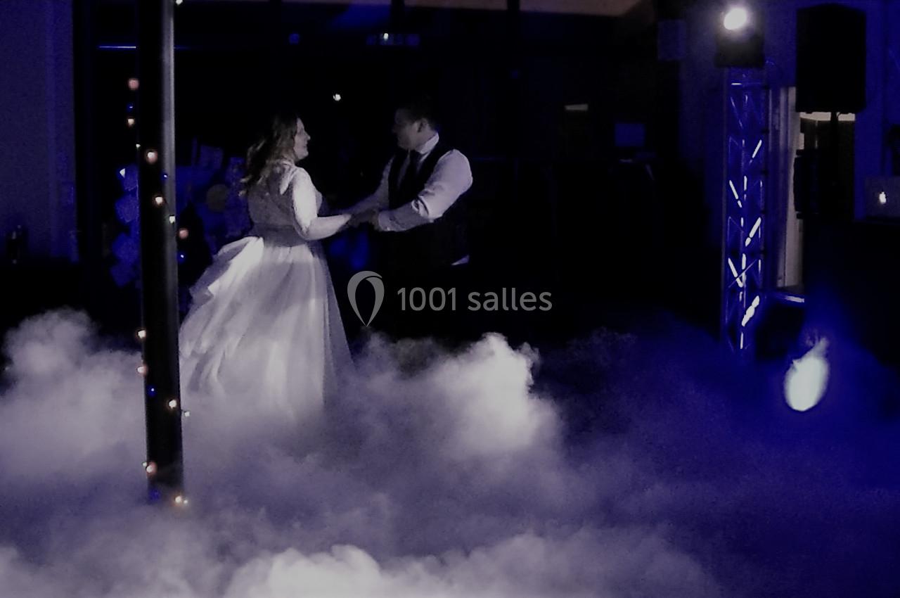 Un couple danse dans une ambiance tamisée avec des lumières bleues et un sol recouvert de fumée.