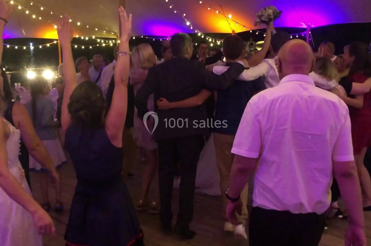 Groupe de personnes dansant sous une tente éclairée par des guirlandes lumineuses lors d'une fête.