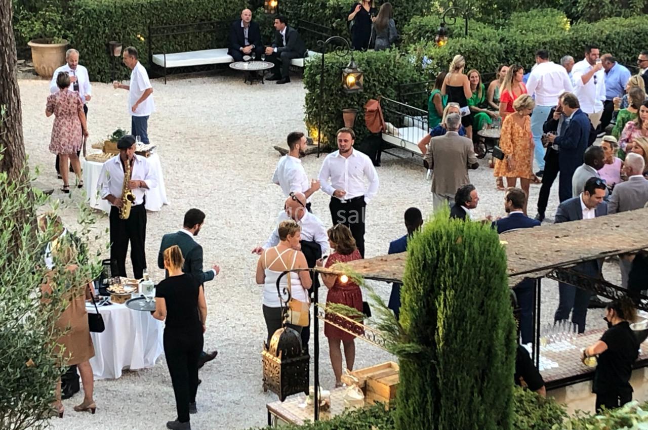 Groupe de personnes discutant et partageant un moment convivial dans un jardin lors d'un événement en plein air.