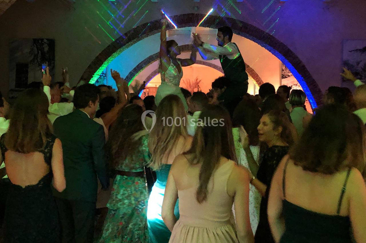Groupe de personnes dansant lors d'une fête, avec des jeux de lumière colorés et une ambiance festive.