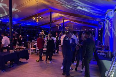 Miniature DJ Le Val (Var) - Enjoy-Your-Event #36 Personnes discutant dans une salle éclairée de lumières bleues, avec tables de buffet et décoration festive.