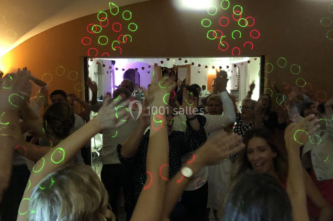 Groupe de personnes dansant sous des lumières colorées dans une ambiance festive en intérieur.