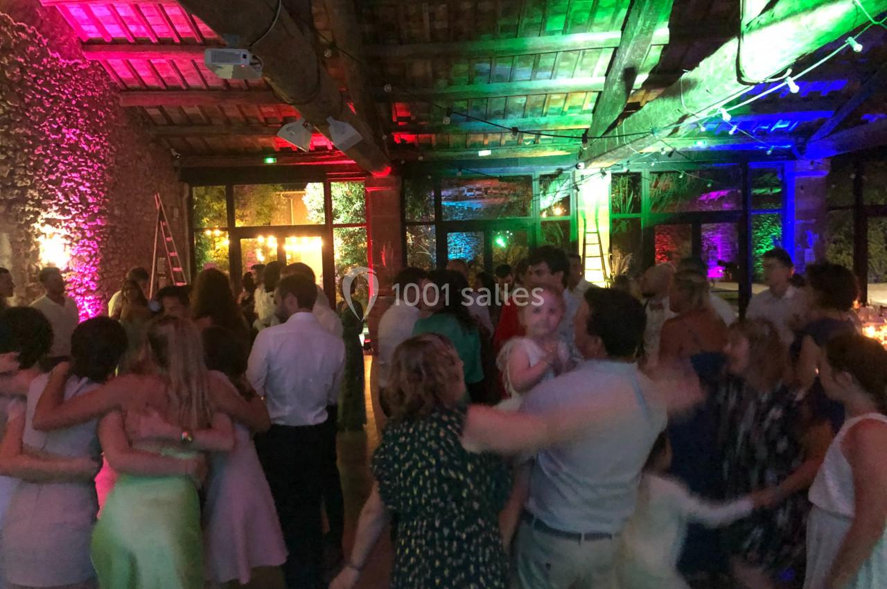 Groupe de personnes dansant dans une salle éclairée par des lumières colorées, ambiance festive en soirée.