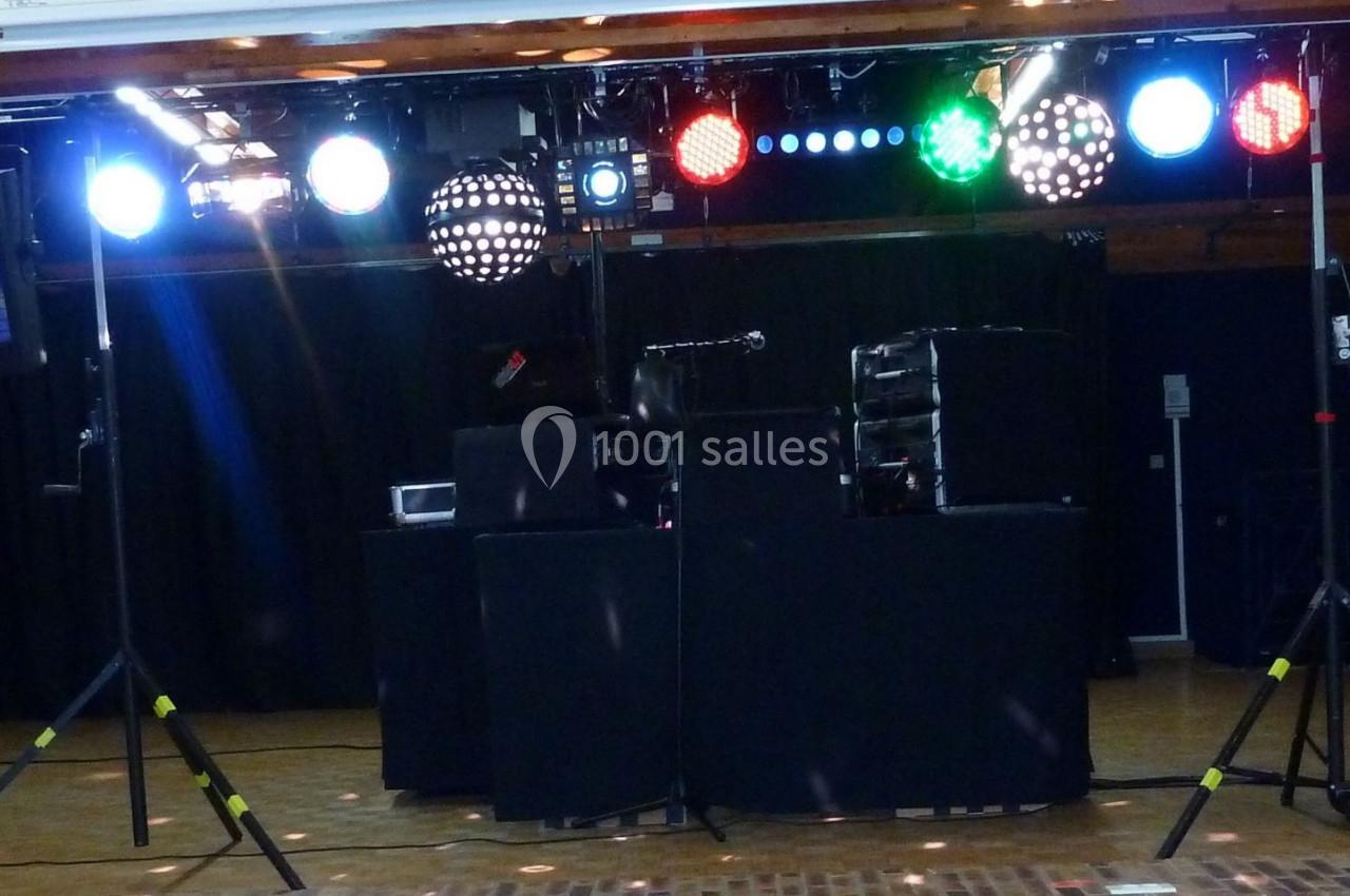 Installation de matériel de sonorisation et éclairage sur une scène, avec projecteurs colorés et enceintes.