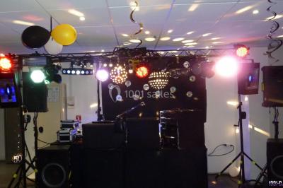 Miniature DJ Buchy (Seine-Maritime) - Djmanfred - Animmix #14 Homme souriant debout devant un micro, portant une chemise noire avec un gilet rayé, fond marron.