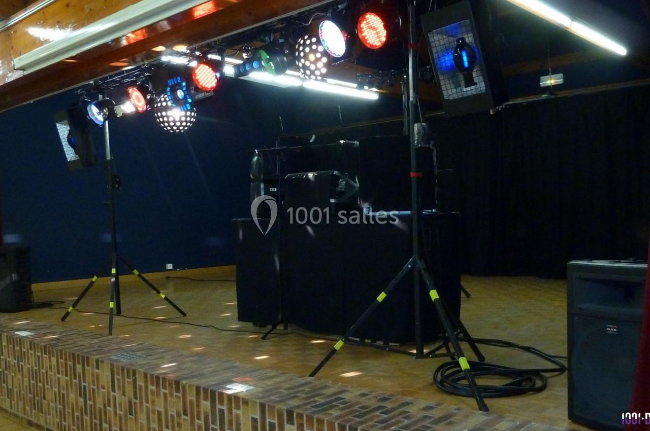 Installation de matériel de sonorisation et d'éclairage sur une scène en intérieur, prête pour un événement.