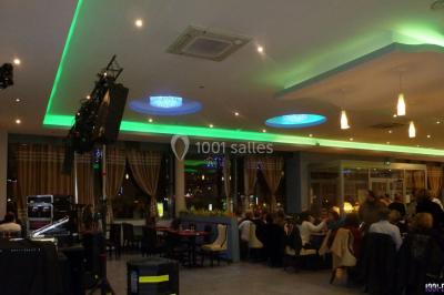 Miniature DJ Buchy (Seine-Maritime) - Djmanfred - Animmix #7 Homme souriant debout devant un micro, portant une chemise noire avec un gilet rayé, fond marron.