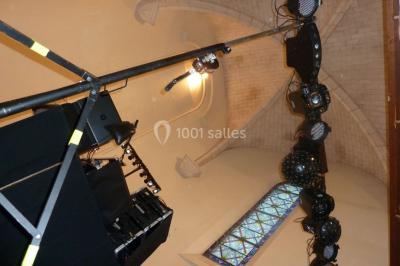 Miniature DJ Buchy (Seine-Maritime) - Djmanfred - Animmix #12 Homme souriant debout devant un micro, portant une chemise noire avec un gilet rayé, fond marron.