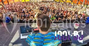 Miniature DJ Buchy (Seine-Maritime) - Djmanfred - Animmix #18 Homme souriant debout devant un micro, portant une chemise noire avec un gilet rayé, fond marron.