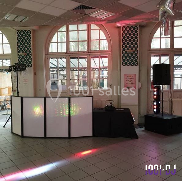 Installation de matériel de sonorisation et éclairage dans une salle avec grandes fenêtres et carrelage au sol.