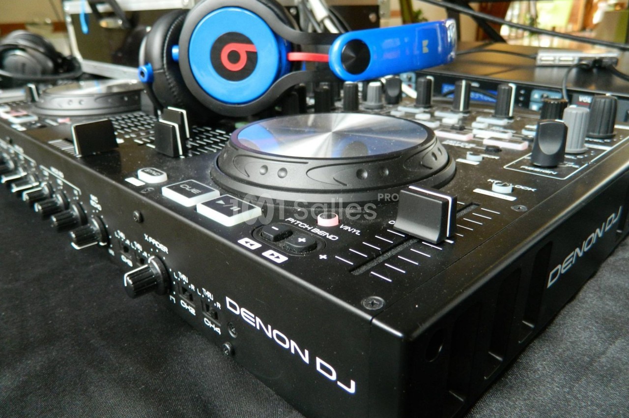 Table de mixage Denon DJ avec des casques audio posés dessus, entourée de divers boutons et commandes.