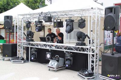 Salle de réception décorée avec des tables dressées, nappes blanches, chaises houssées et arrangements floraux.