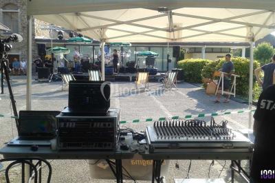 Salle de réception décorée avec des tables dressées, nappes blanches, chaises houssées et arrangements floraux.