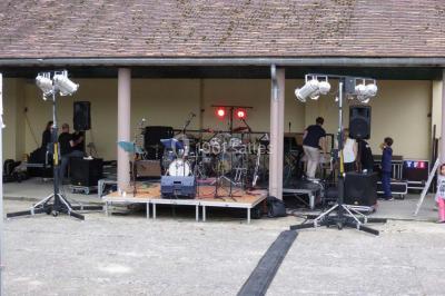 Salle de réception décorée avec des tables dressées, nappes blanches, chaises houssées et arrangements floraux.