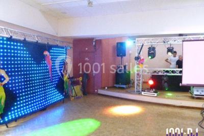 Salle de réception décorée avec des tables dressées, nappes blanches, chaises houssées et arrangements floraux.