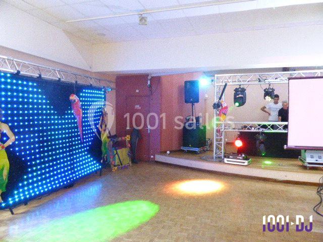 Salle de fête avec éclairage coloré, piste de danse, écran et équipement de sonorisation installé.