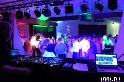 Salle de réception décorée avec des tables dressées, nappes blanches, chaises houssées et arrangements floraux.