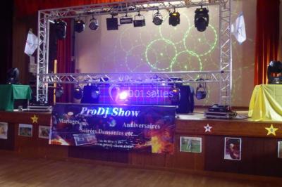 Salle de réception décorée avec des tables dressées, nappes blanches, chaises houssées et arrangements floraux.