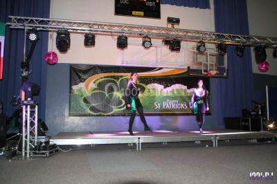 Salle de réception décorée avec des tables dressées, nappes blanches, chaises houssées et arrangements floraux.