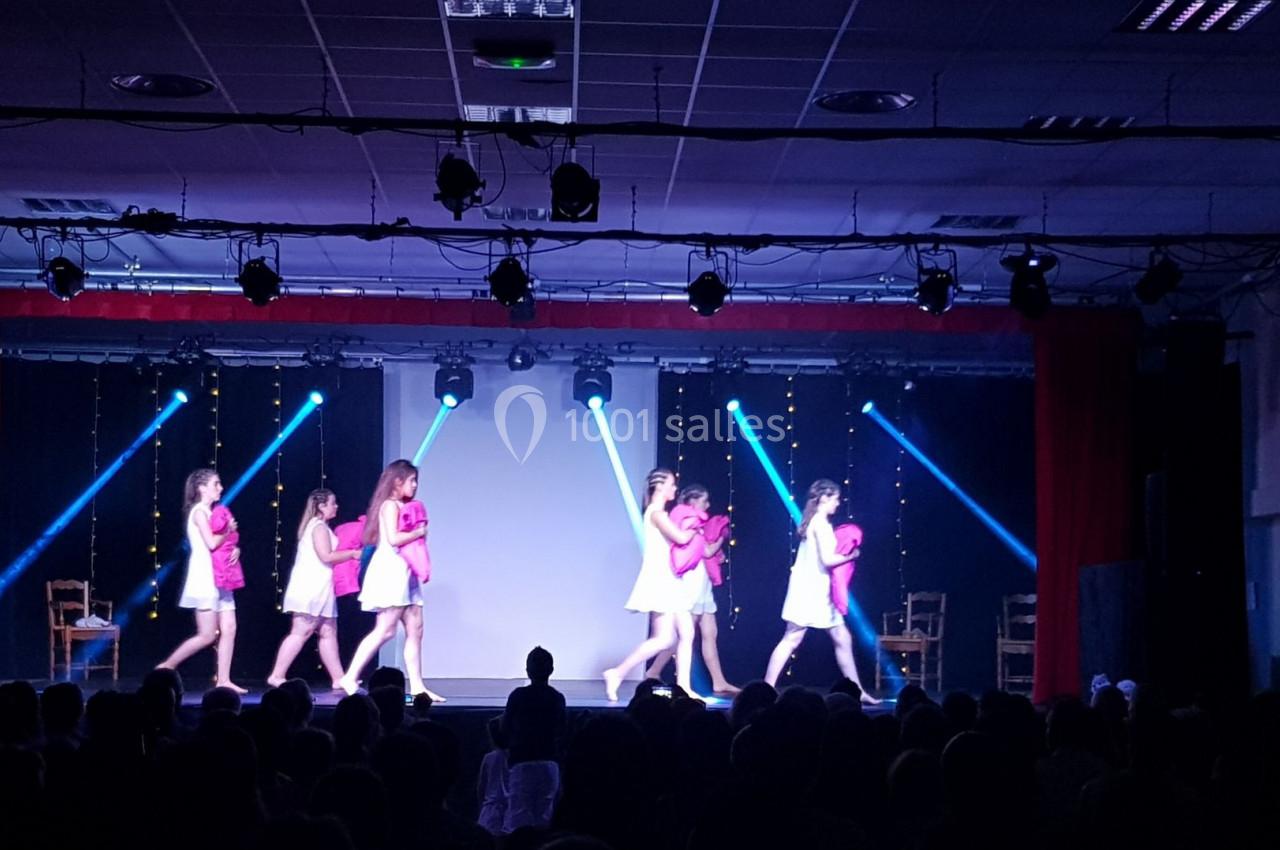 Des danseuses en tenue rose et blanche exécutent une chorégraphie sur une scène éclairée par des projecteurs.