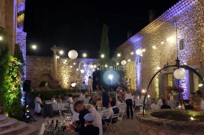 Salle avec éclairage de scène coloré, piste de danse illuminée, tables sur les côtés et matériel audio en arrière-plan.