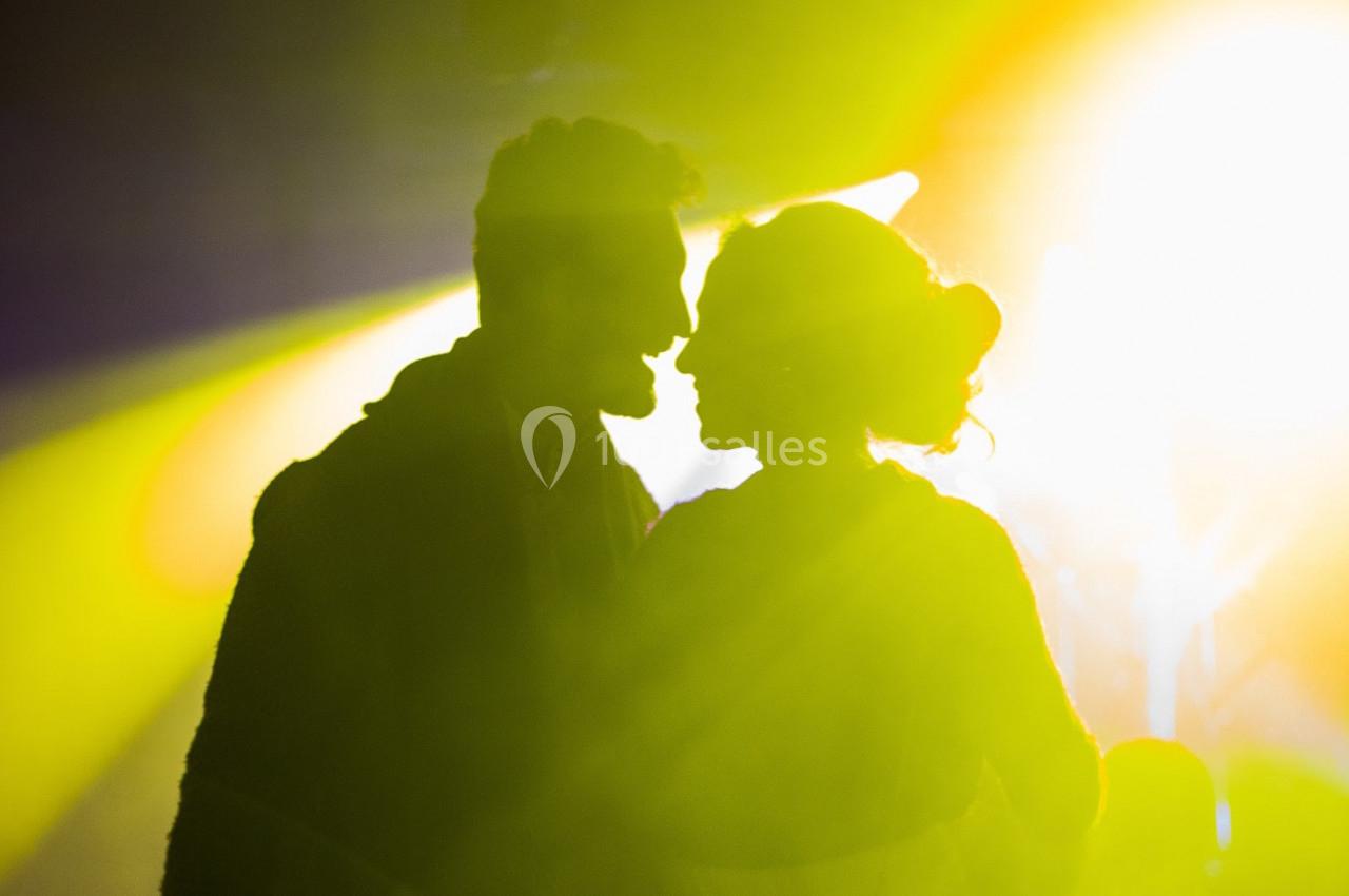 Silhouettes d'un homme et d'une femme se faisant face sous une lumière vive jaune et blanche.
