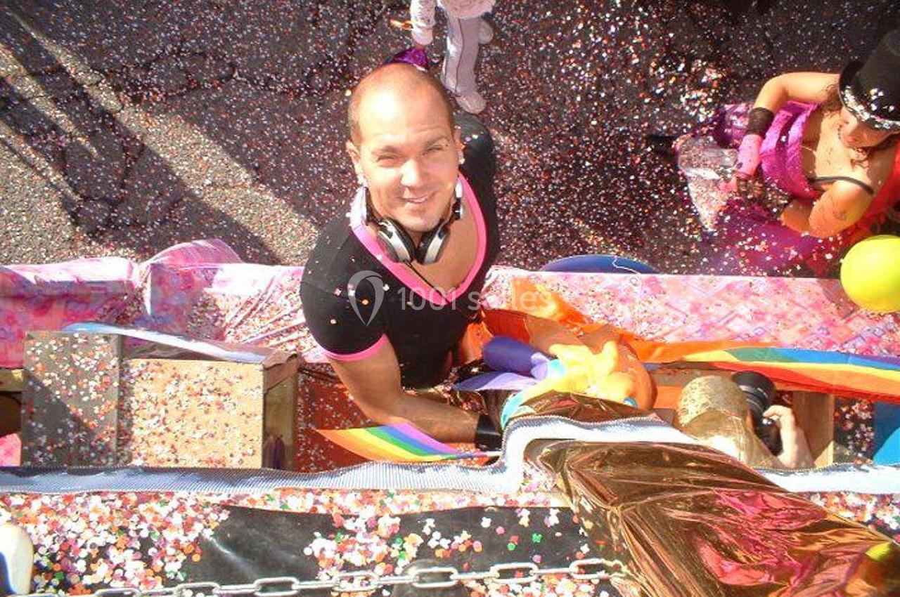 Homme souriant sur un char décoré, entouré de confettis colorés lors d'une parade festive.