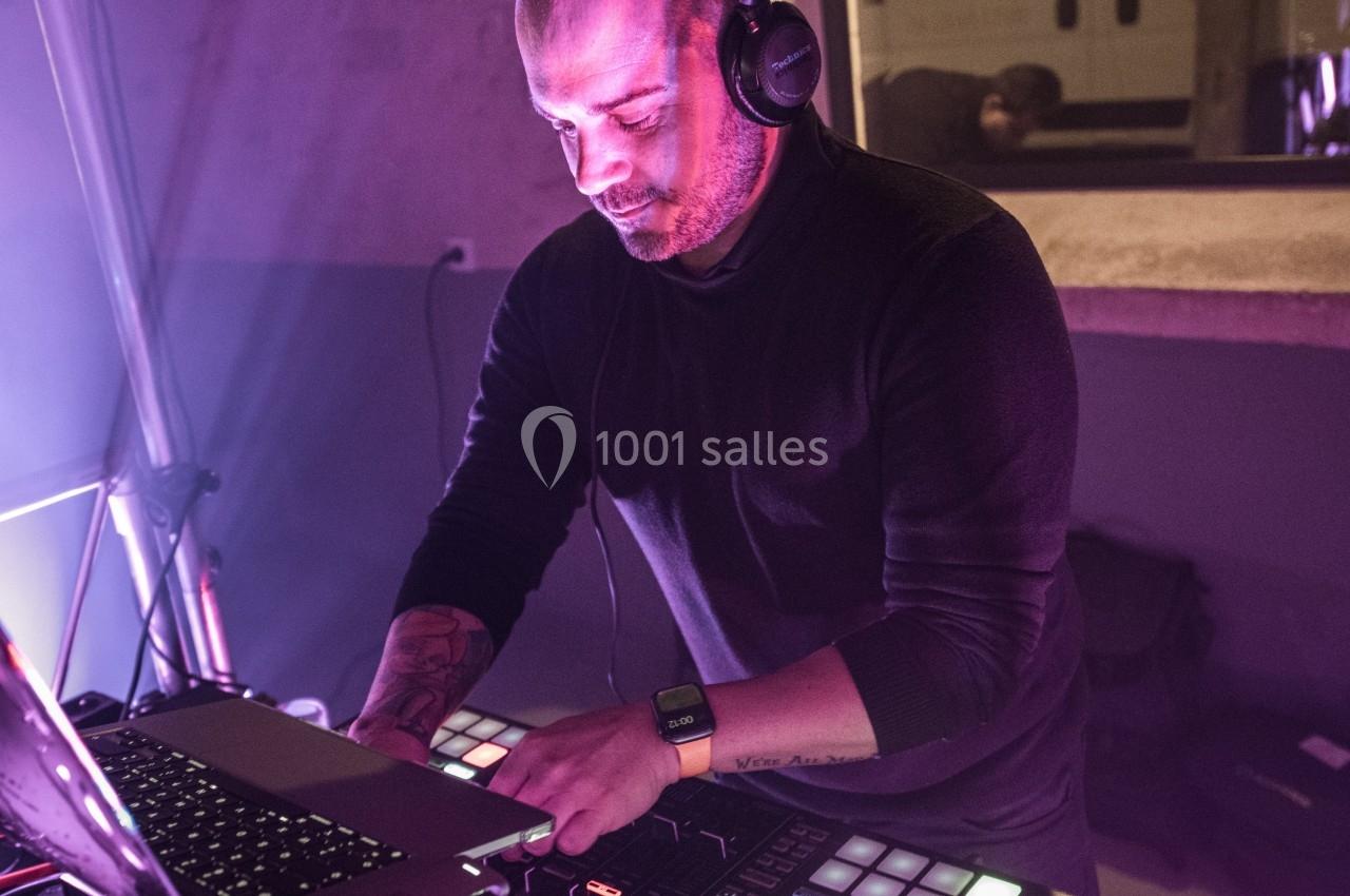 Un DJ mixant de la musique sur une console avec un ordinateur portable dans un environnement éclairé par des lumières…