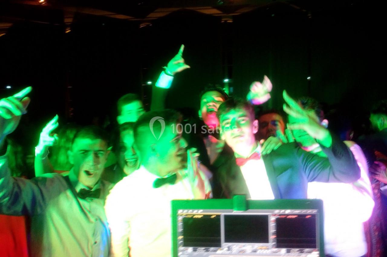 Des jeunes en tenue de soirée dansent et s'amusent sous des lumières colorées dans une ambiance festive.